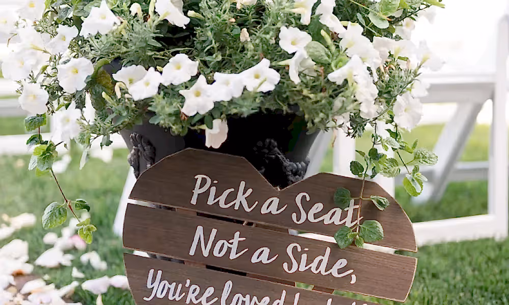 Wooden wedding sign that says pick a seat,not a side you're loved by both the groom and bride during ceremony in Ballyowen Wedding Garden.
