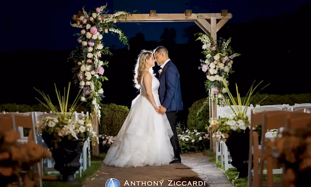 Bride and groom stand under arch in Ballyowen Wedding Garden at nighttime.