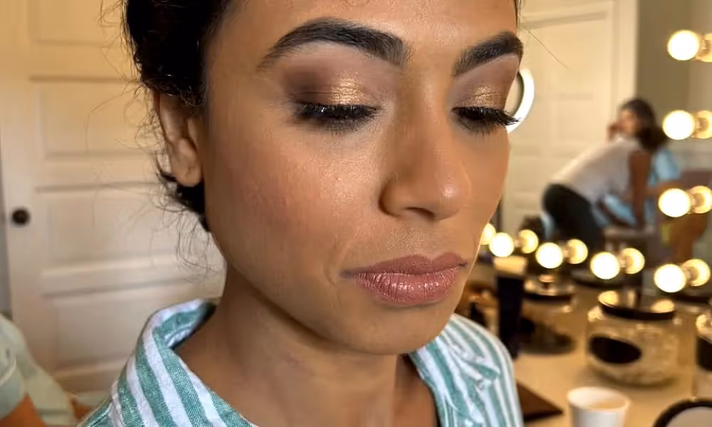 Woman closes her eyes to show off golden eyeshadow. 