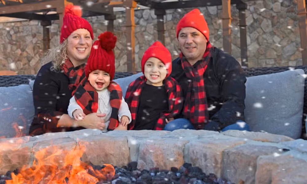 Family of four bundled up by the fire. 