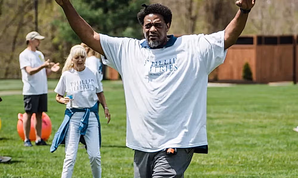 Man raises arms in the air.