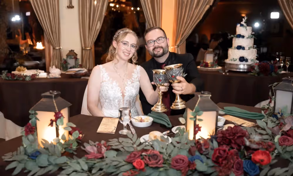 Bride and groom cheers as they sit at honeymoon table during their Black Bear wedding.
