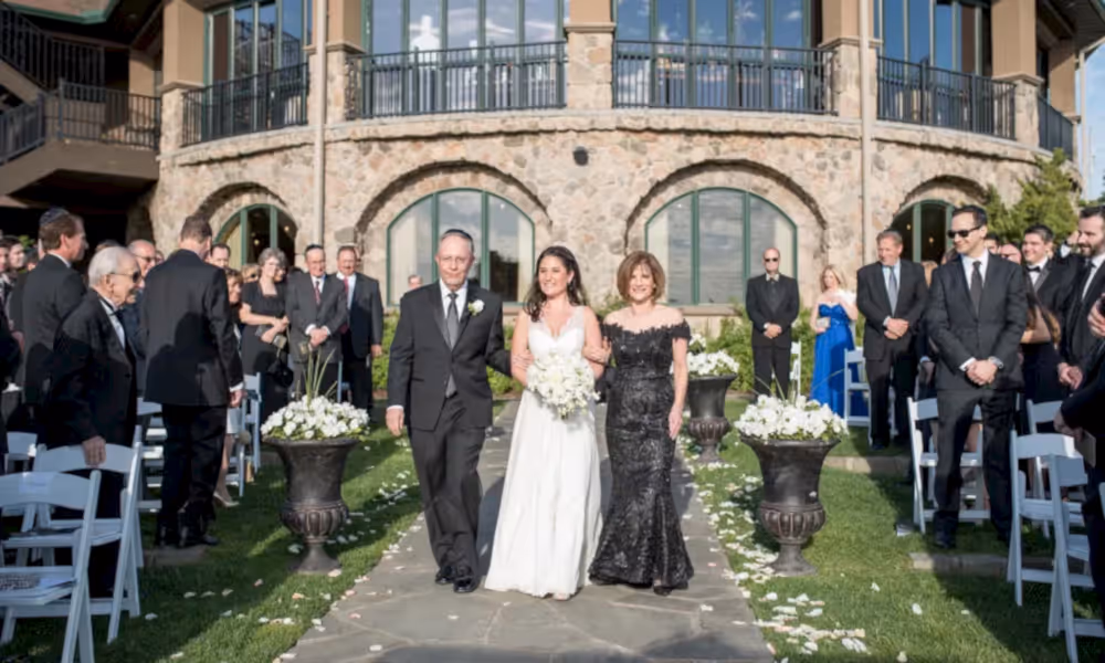 Bride walking down aisle with parents at the wedding garden