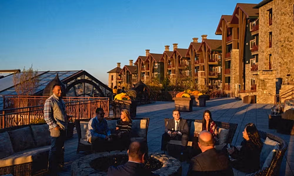 Group of people sitting by the fire pit on the terrace at Grand Cascades Lodge