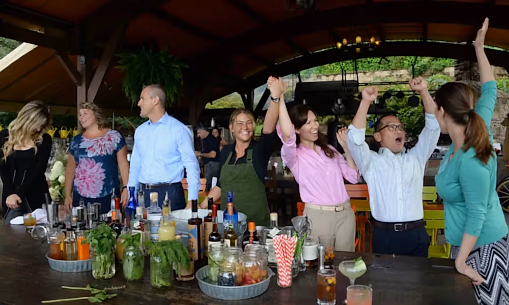 Coworkers cheering as they compete in a mixology teambuilding activity.