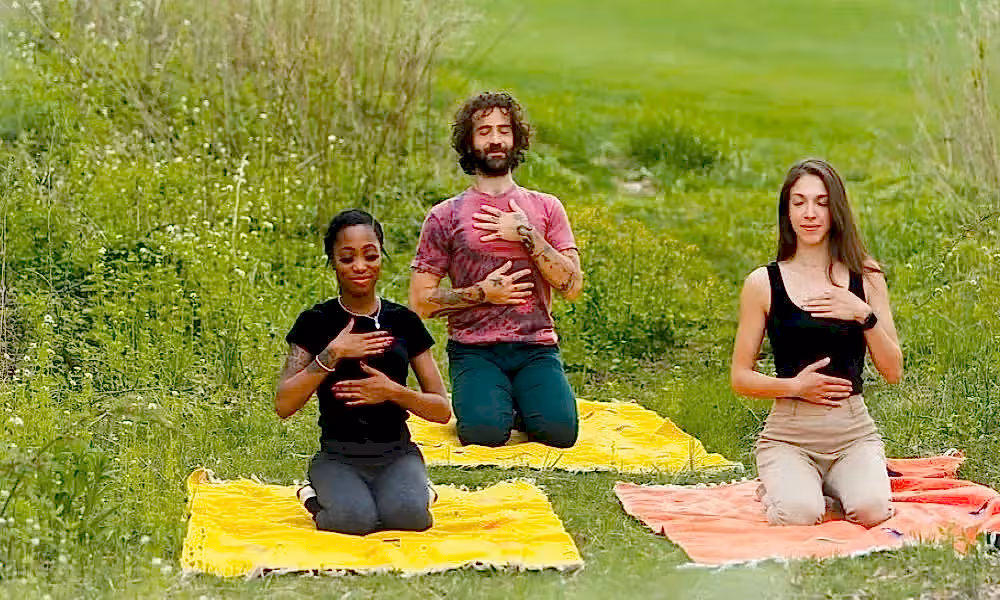 Group of three people meditating in a field in New Jersey.