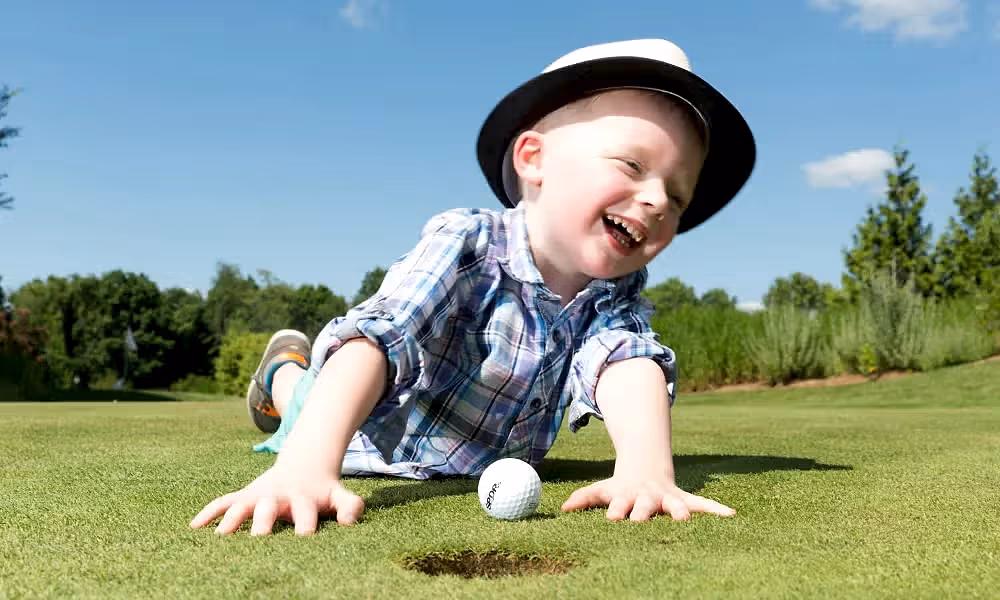 Boy smiling and laying on a golf course
