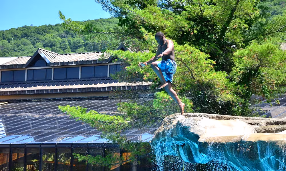 Young boy cannonballing off cliff jump at Minerals Hotel
