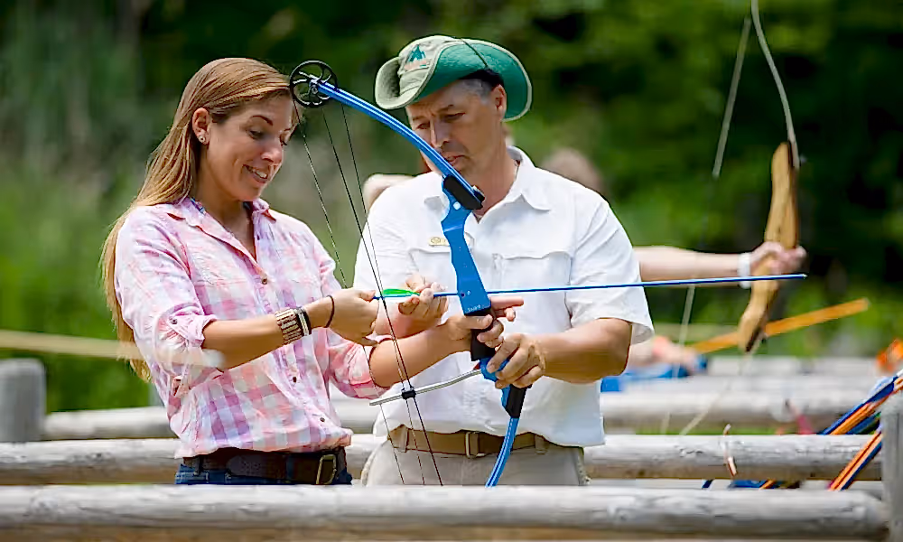 Archery instructor helping woman.