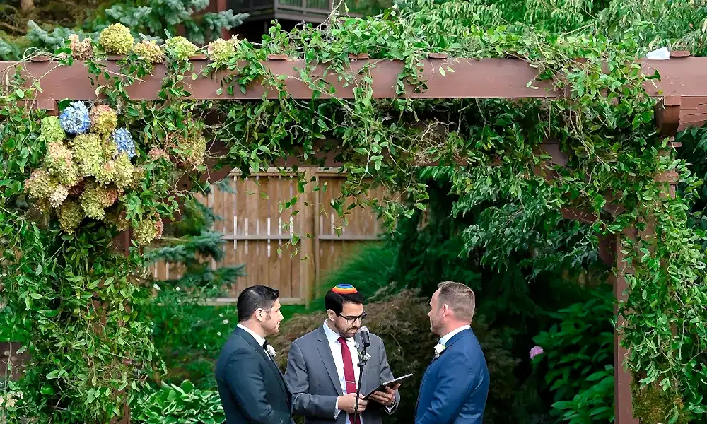Wedding ceremony for two grooms standing with their officiant.
