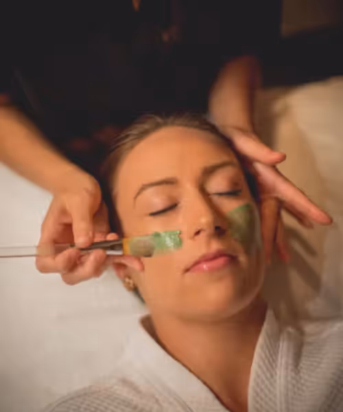 Green face mask being applied to woman's face.