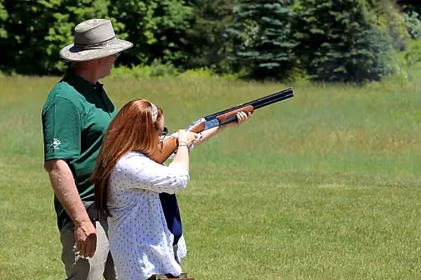 Instructor helping woman shoot laser clays.