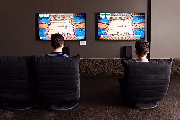 Two children sitting in front of two tvs playing video games.