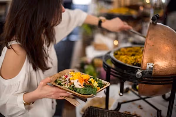 Woman scooping rice onto her plate during buffet.