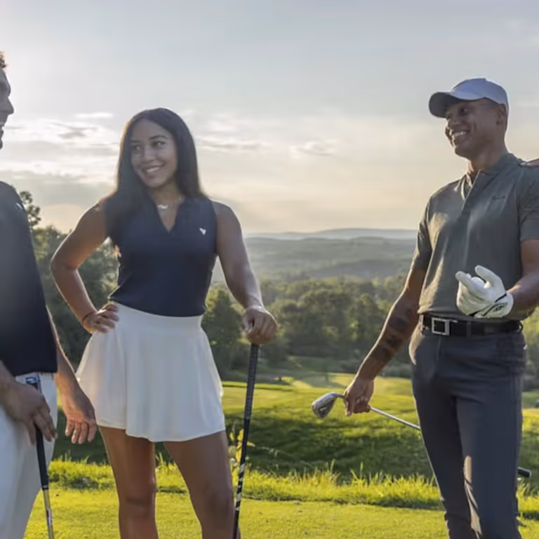 Two women and two men stand together on golf course, 