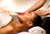Woman laying on table with facialists hands on her chin and forehead. 